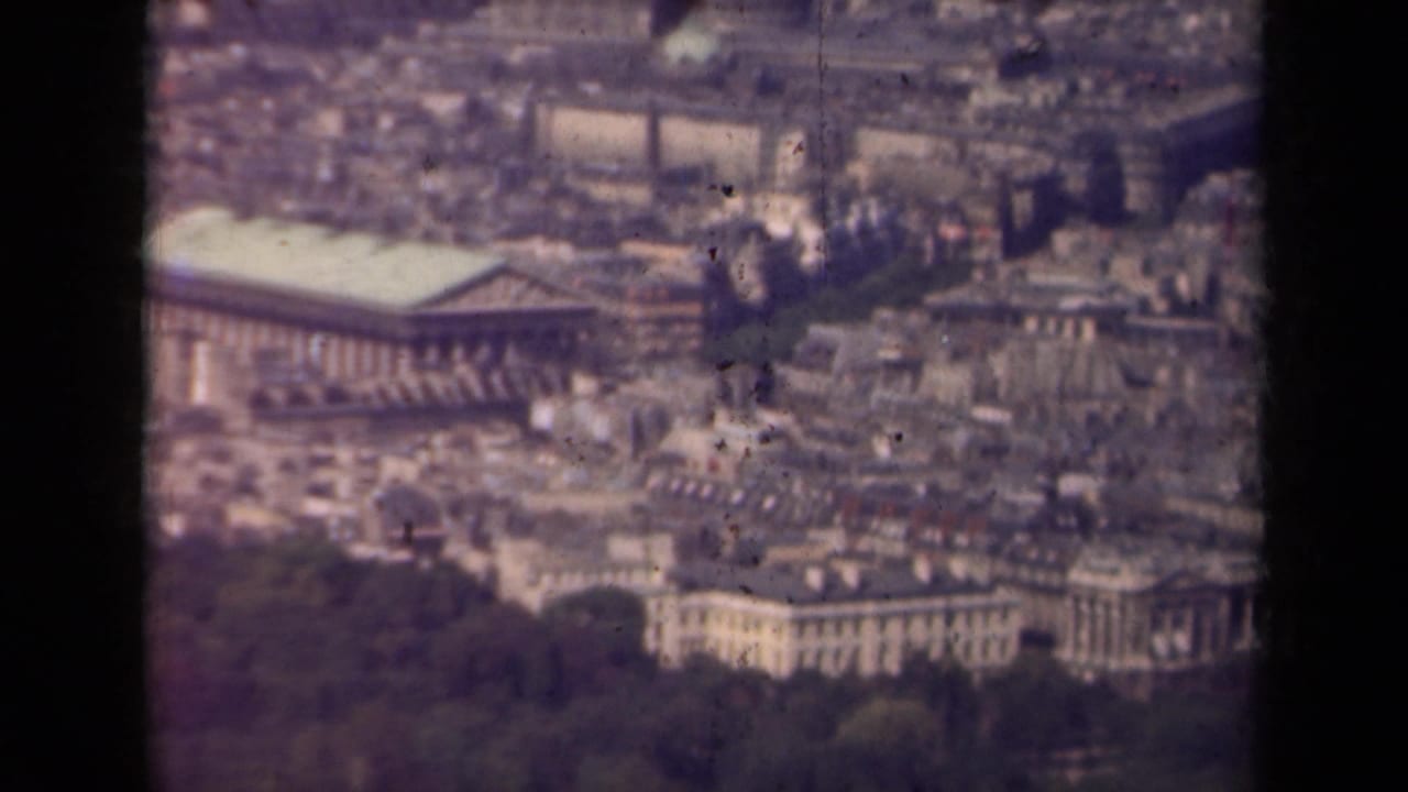 Aerial view of Paris with a large colonnaded building and dense city blocks.