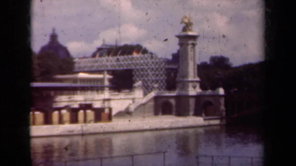 1939 Paris home-movie view of a waterside monument with a gilded statue, reflective water, and distant domed architecture.