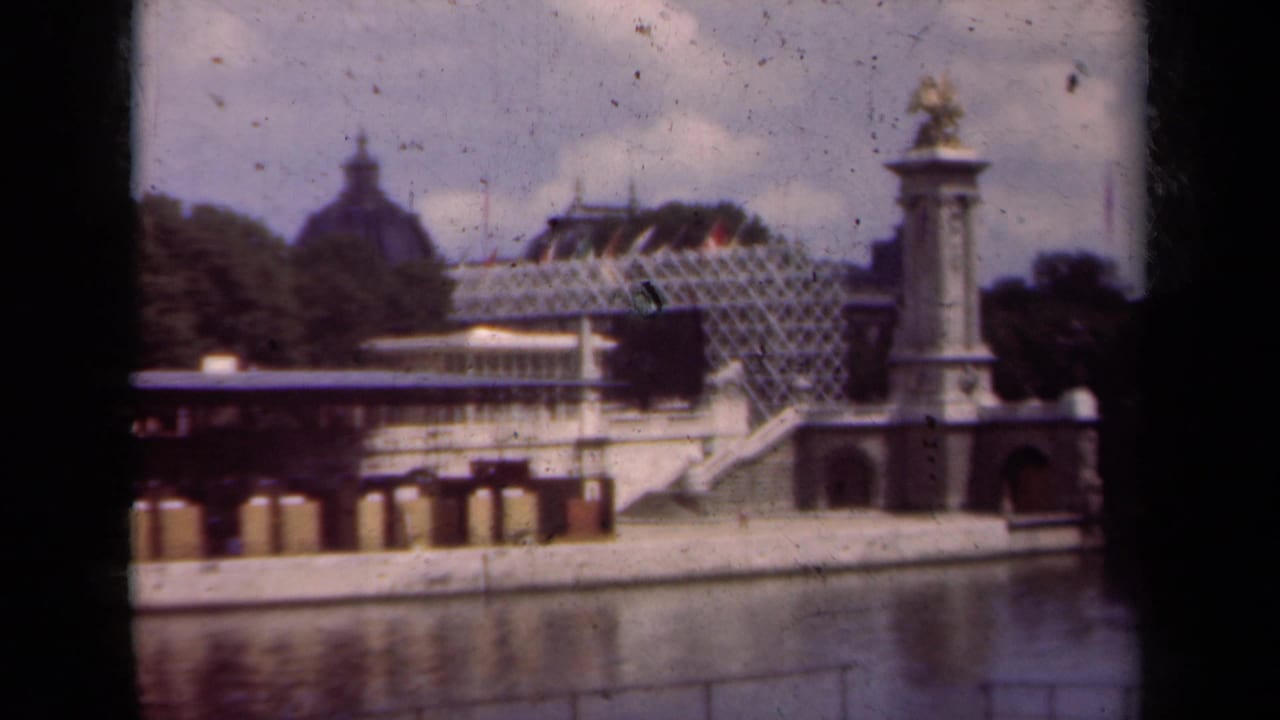Paris waterfront with a stone bridge, domed building, glass-roofed structure, trees, and gilded statue column.