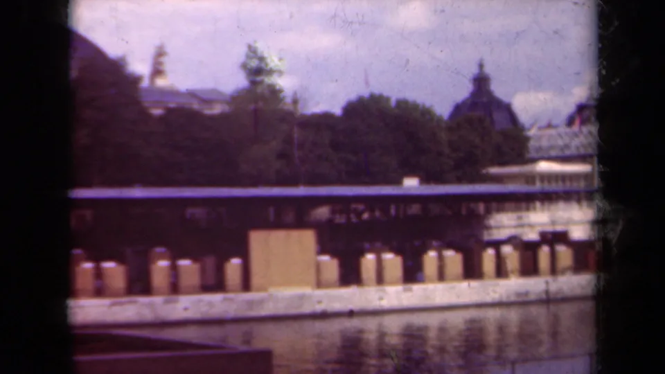 1939 Paris home-movie view across water toward a tree-lined bank and partially hidden urban buildings.