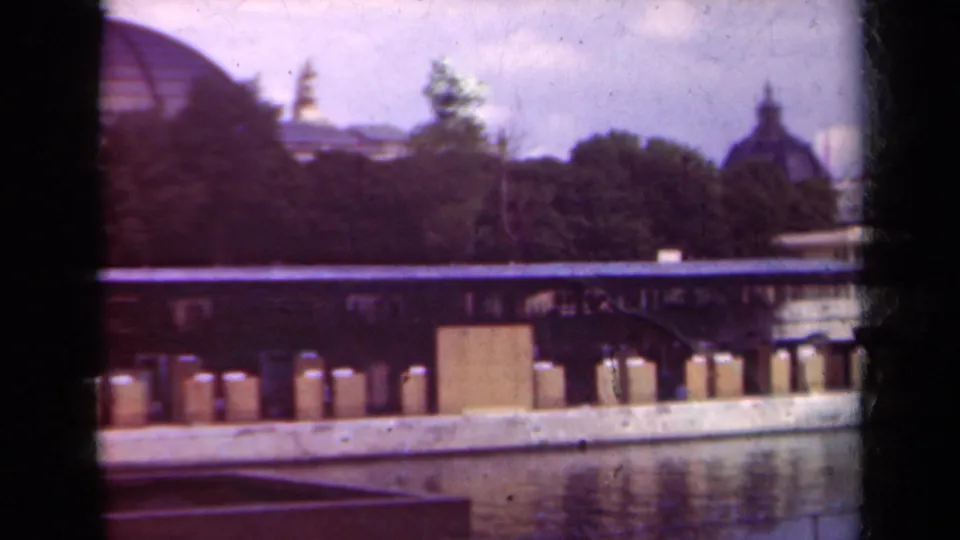 1939 Paris riverfront frame with water reflections, repeated dock posts, trees, and a distant domed building.