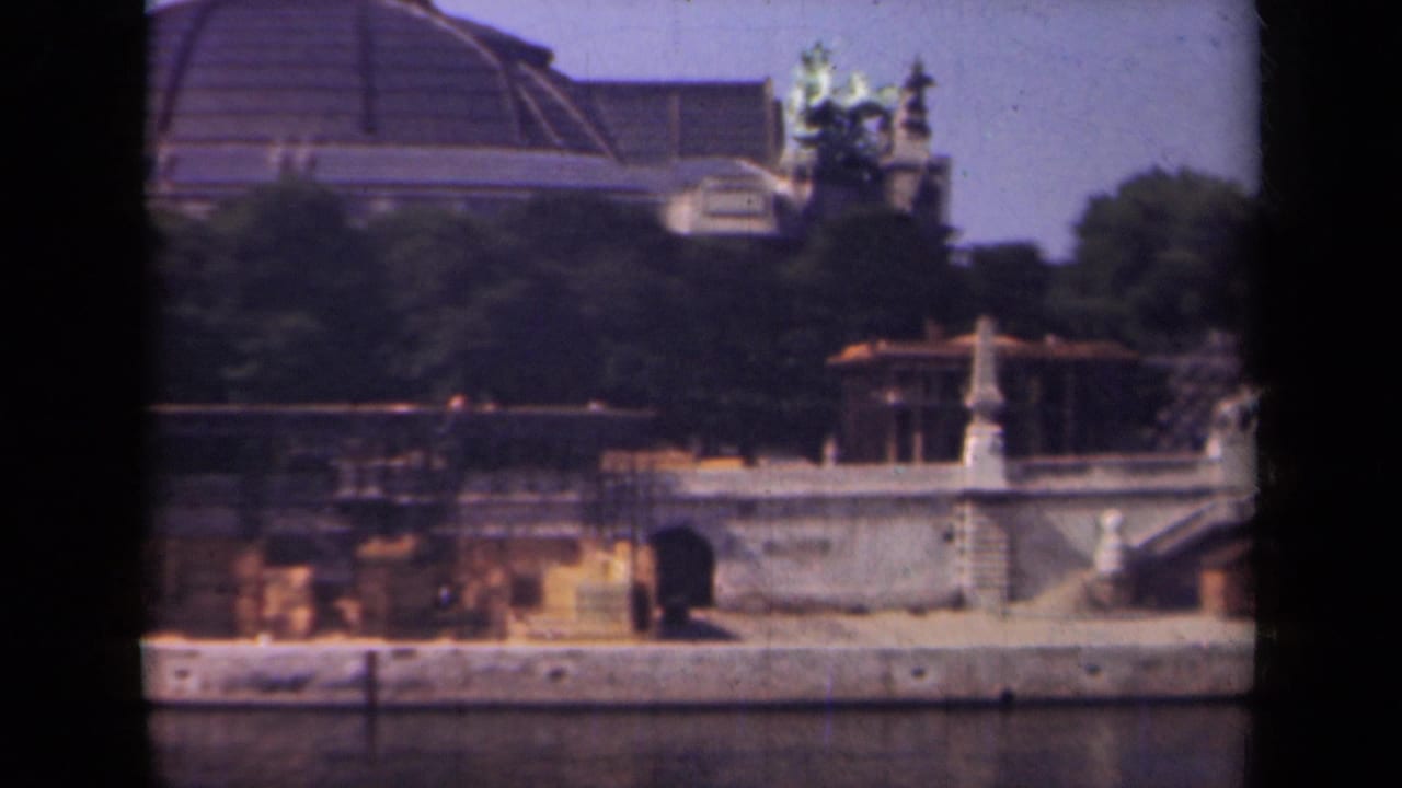 Paris waterway with stone embankment, arched opening, trees, and a domed building beyond.