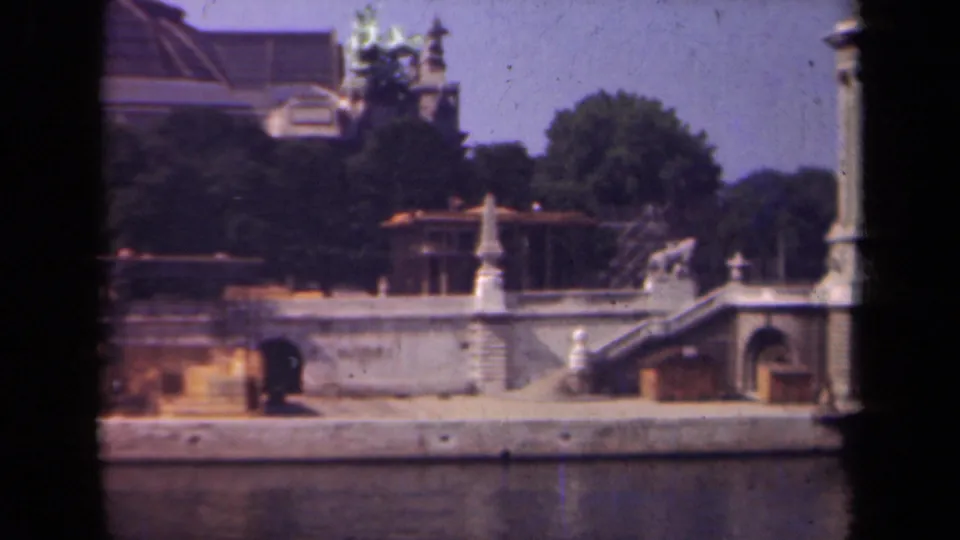1939 Paris footage showing a stone riverside structure with stairs, a tall column, trees, and ornate architectural details.