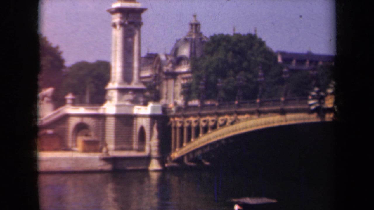 1939 Paris frame with the bridge's stone pylon and curved railing prominent above the river, backed by trees and civic buildings.