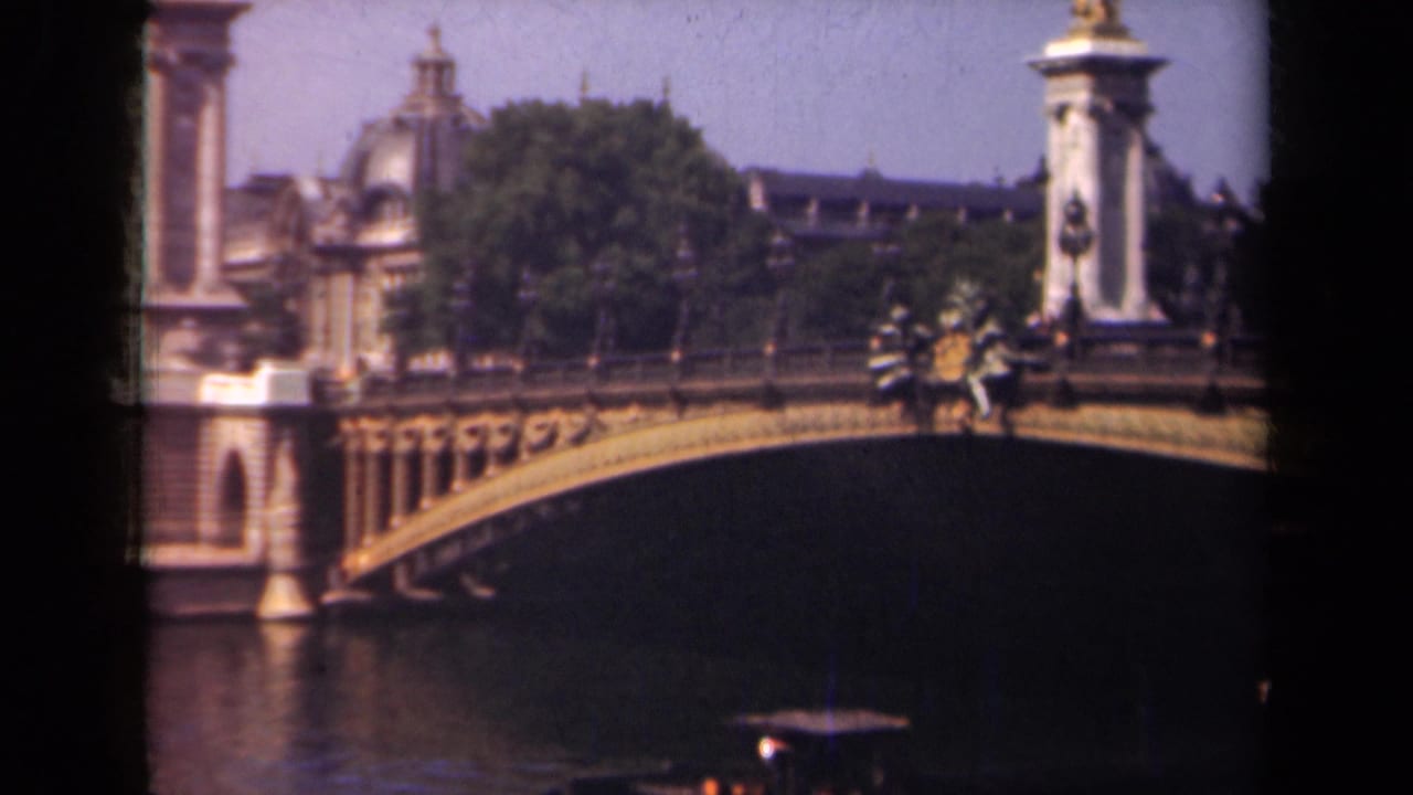 Pont Alexandre III arch over the Seine with ornate bridge columns and a small boat below.