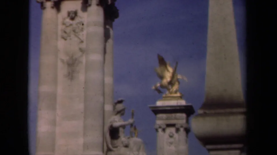 Late-1930s Paris 8mm frame showing Pont Alexandre III stonework, gilded winged ornament, seated figure detail, and a rounded lamp form.
