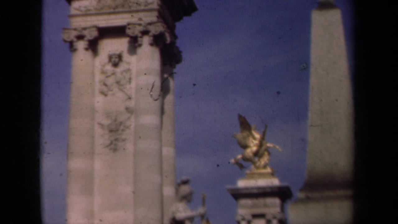 Carved stone monument column with a gilded winged horse sculpture and blue sky behind it.