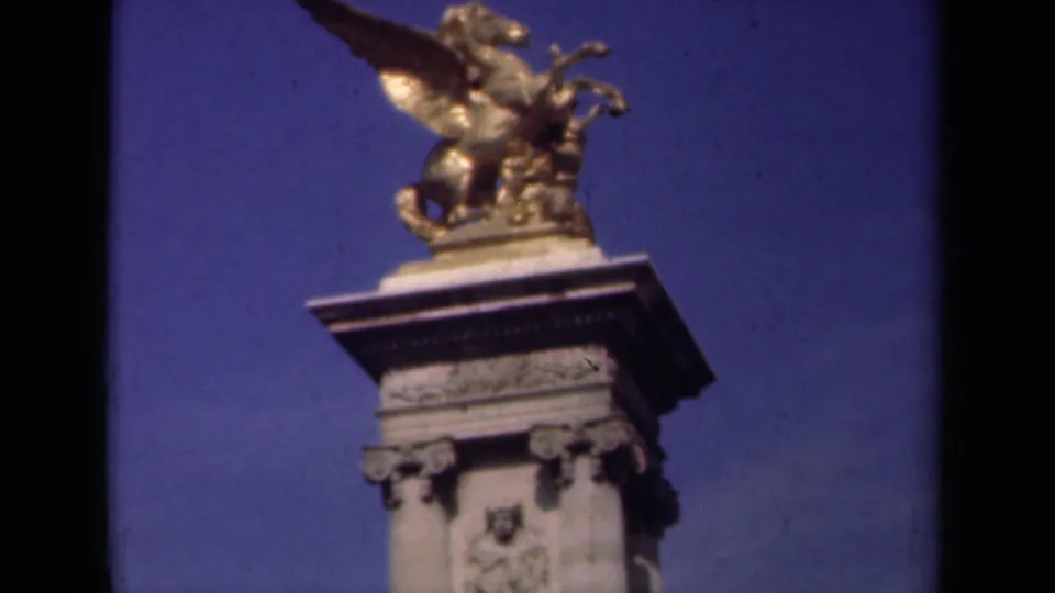 1939 Paris frame centered on a gilded winged horse sculpture atop an ornate stone pedestal, with blue sky and 8mm frame-edge darkening.