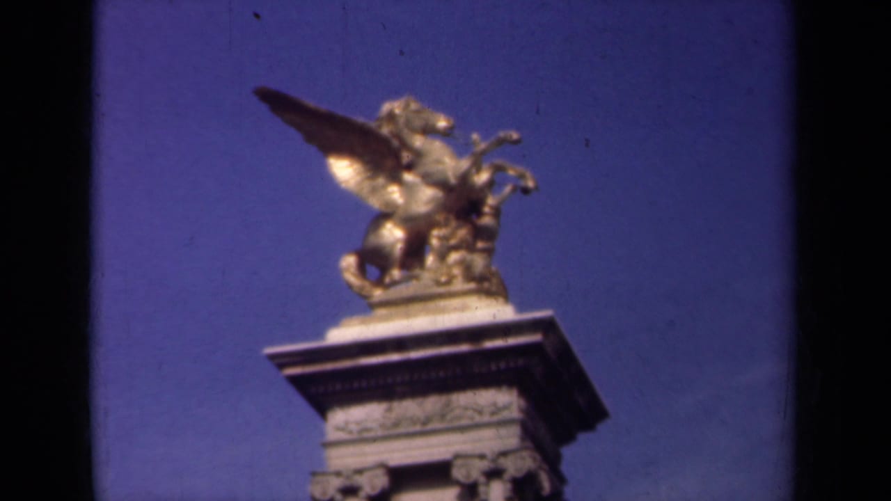 1939 Paris frame with the gilded winged horse statue and upper pedestal centered against a blue sky, with visible 8mm gate edges.