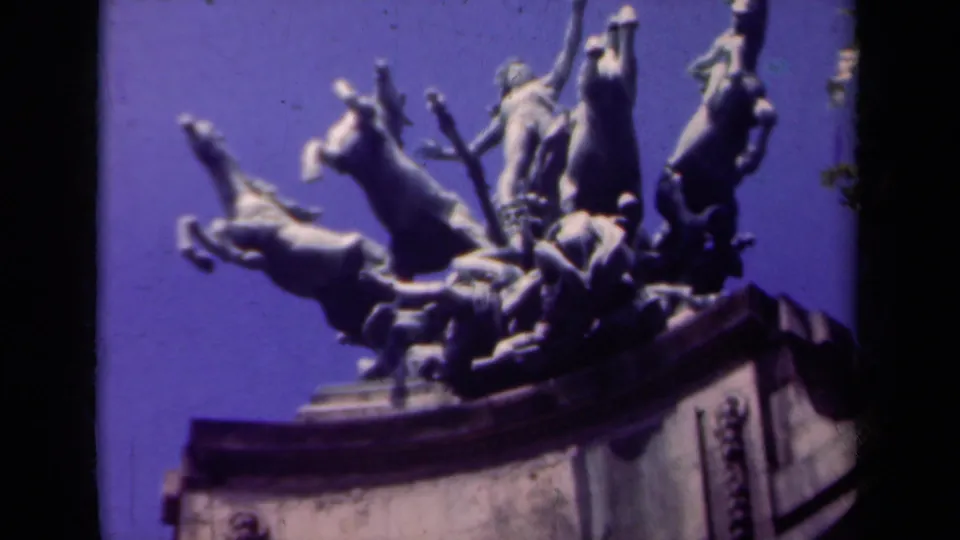 Close view of a Paris monumental sculpture showing rearing horses and human figures against a saturated blue-purple sky.