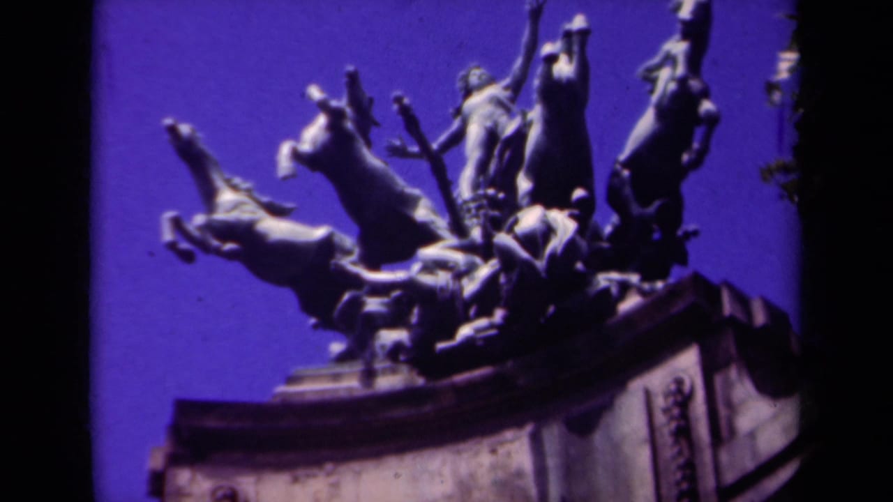 Low-angle view of a sculptural group with rearing horses, a central figure, and a raised sword against a blue-purple sky.