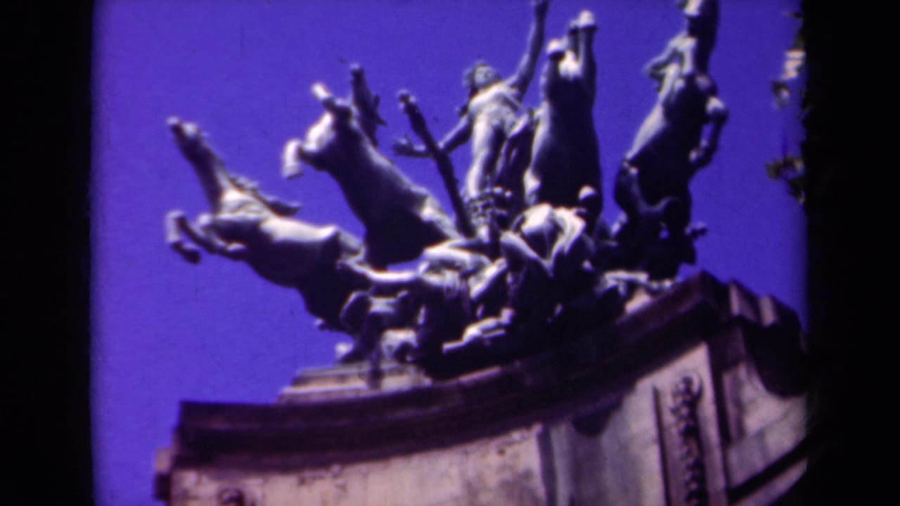 1939 Paris home-movie frame showing the upper portion of a monumental horse sculpture with a sword-bearing figure and stone pedestal.