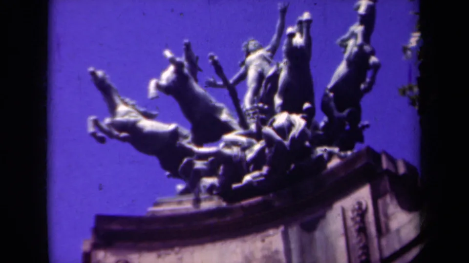 1939 Paris 8mm frame with soft focus on a public monument of rearing horses and a central sword-bearing figure above a stone base.