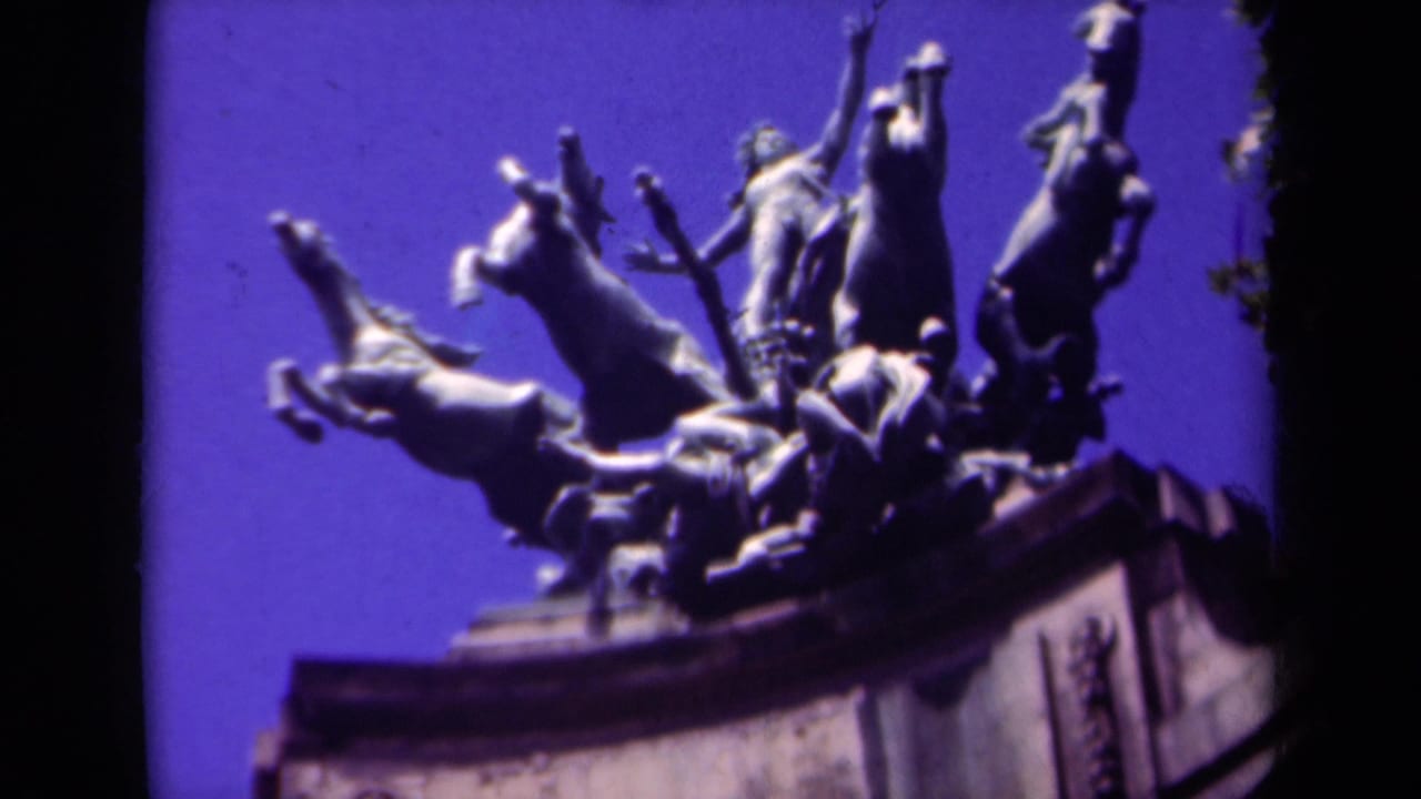 Close-up of a sculptural group with rearing horses against a purple-blue sky.