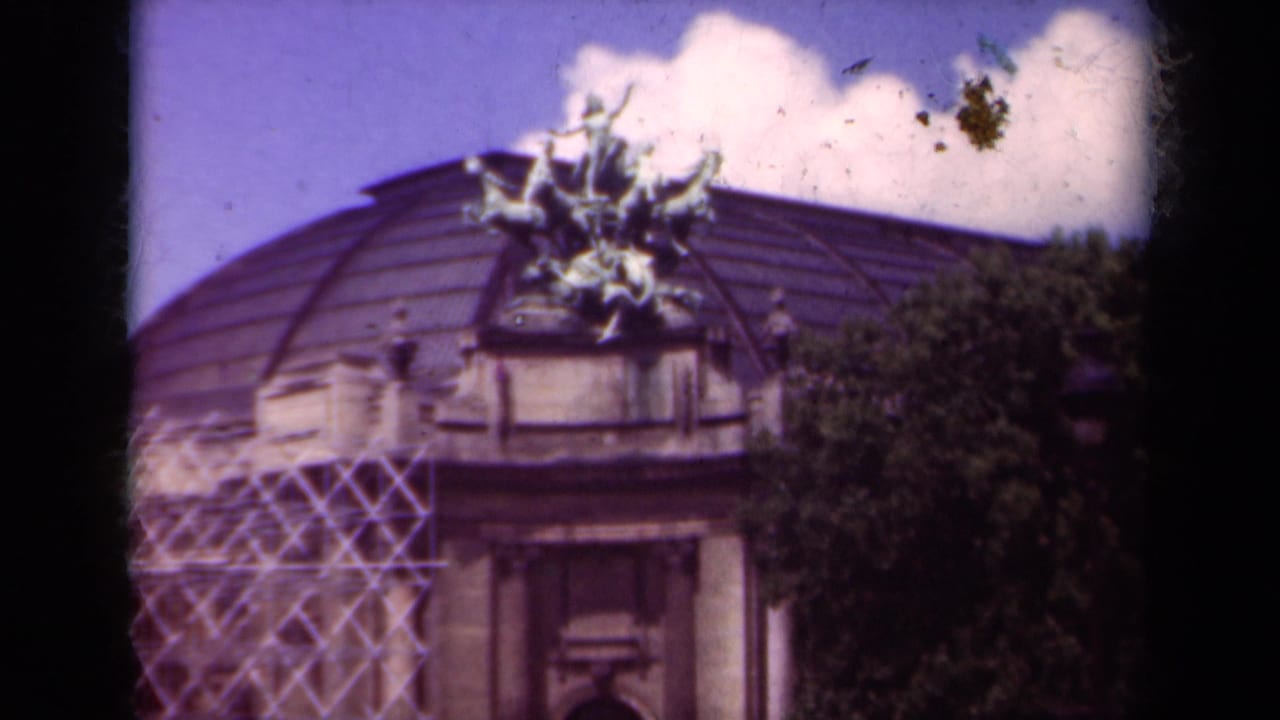 1939 Paris 8mm frame showing a domed public building with sculptural ornament, scaffolding, and a tree at the side.