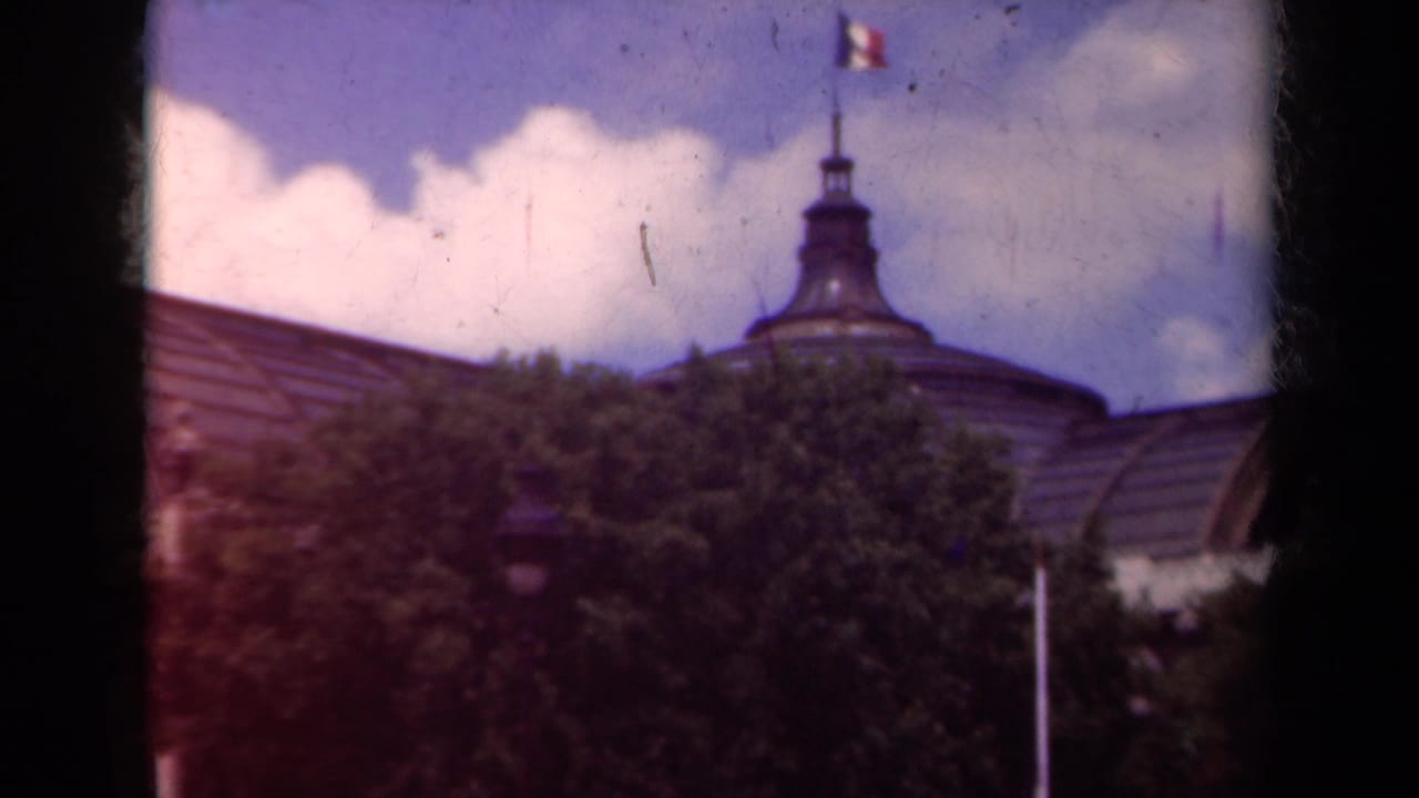 The pan centers on a domed roof feature and French flag above trees in a 1939 Paris exterior view.