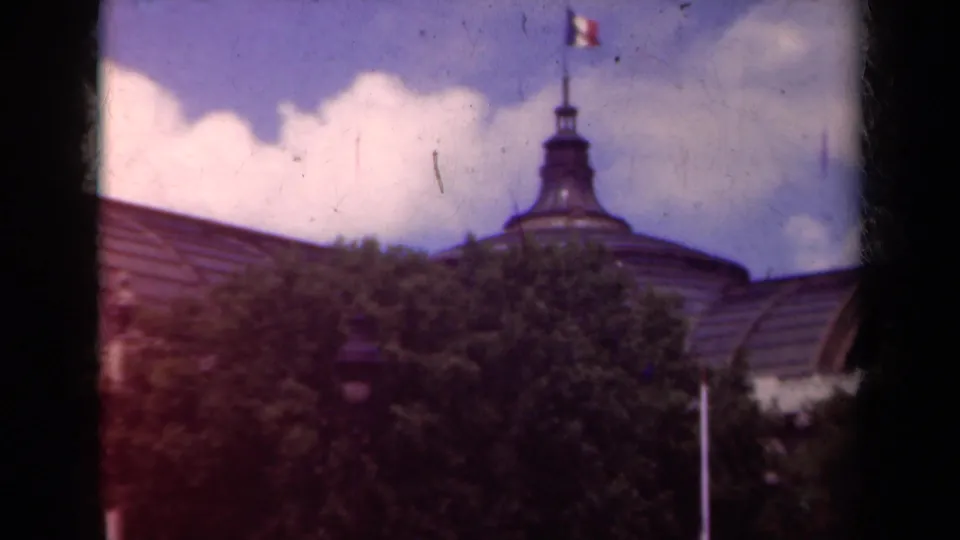The pan centers on a domed roof feature and French flag above trees in a 1939 Paris exterior view.