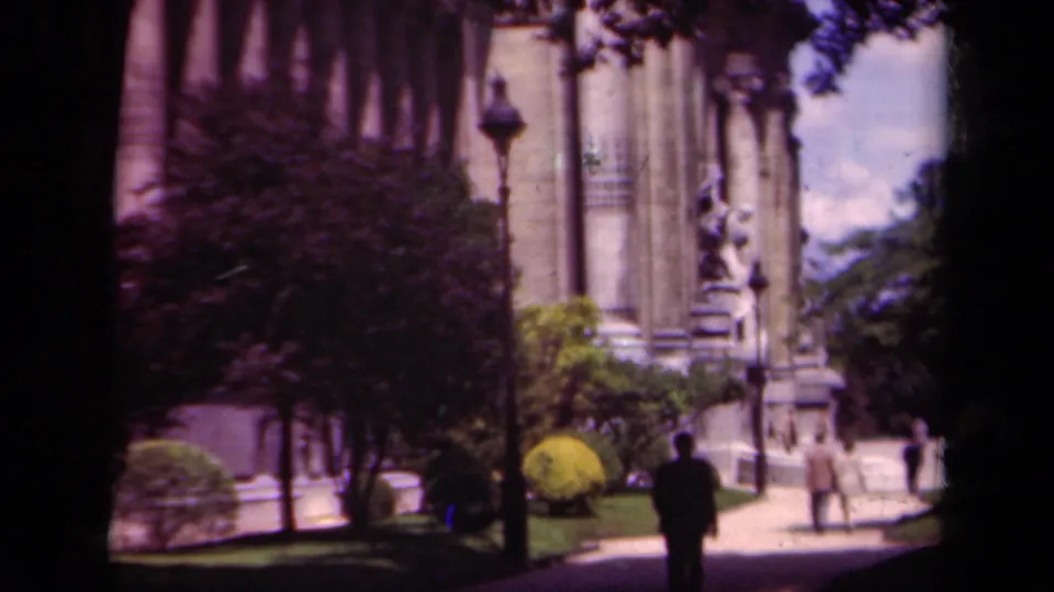 1939 Paris street-level view of a grand building entrance area with trees, statue, pedestrians, and a silhouetted figure in the foreground.