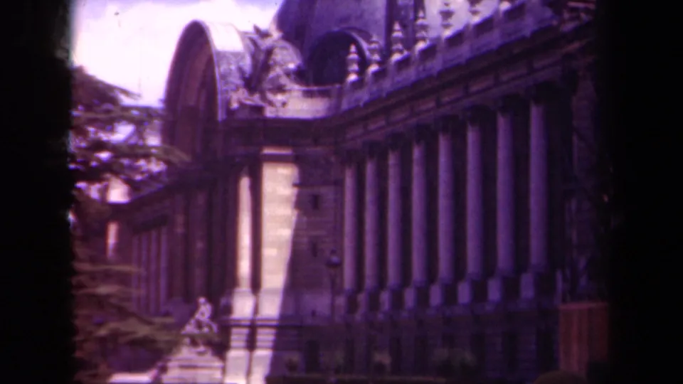 Wider 1939 Paris 8mm view showing a classical building corner, arched roofline, columns, sculpture, trees, lawn, and formal flowerbed.