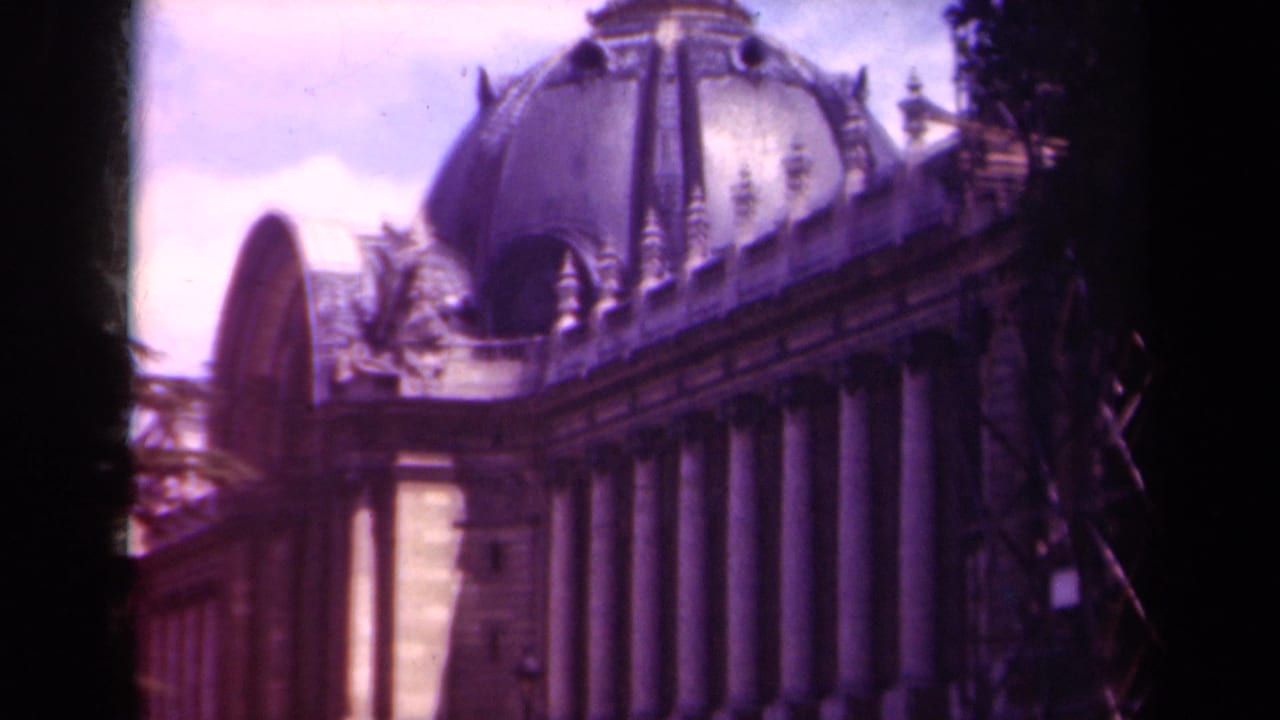 Low-angle 1939 Paris view of a domed classical building with columns, roof ornament, pale stone, and soft 8mm color.