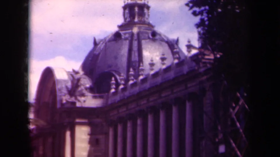 1939 Paris home-movie frame with the camera tilted higher toward a domed roof, arched section, columns, and dark edge shadows.