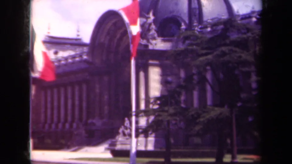1939 Paris frame with a closer Swiss flag beside the flagpole, classical columns, domed architecture, trees, and a strip of lawn.