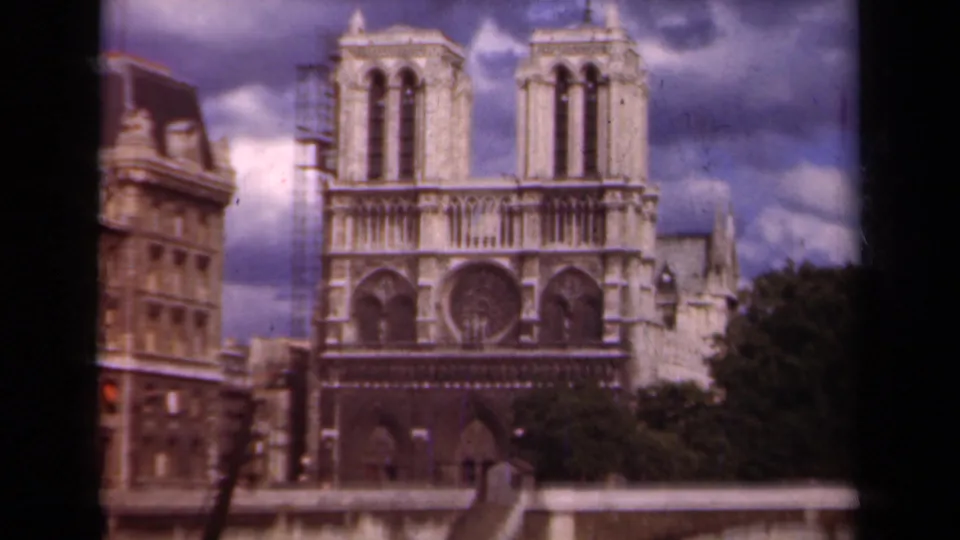 1939 Paris view of Notre Dame across the bridge, showing the rose window, towers, scaffolding, and trees.