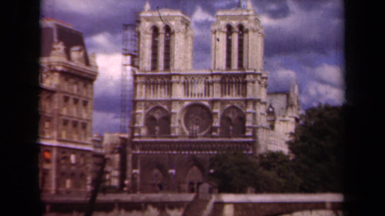 Paris home-movie frame of Notre-Dame Cathedral in 1939, with the facade centered and scaffolding visible along the left tower.
