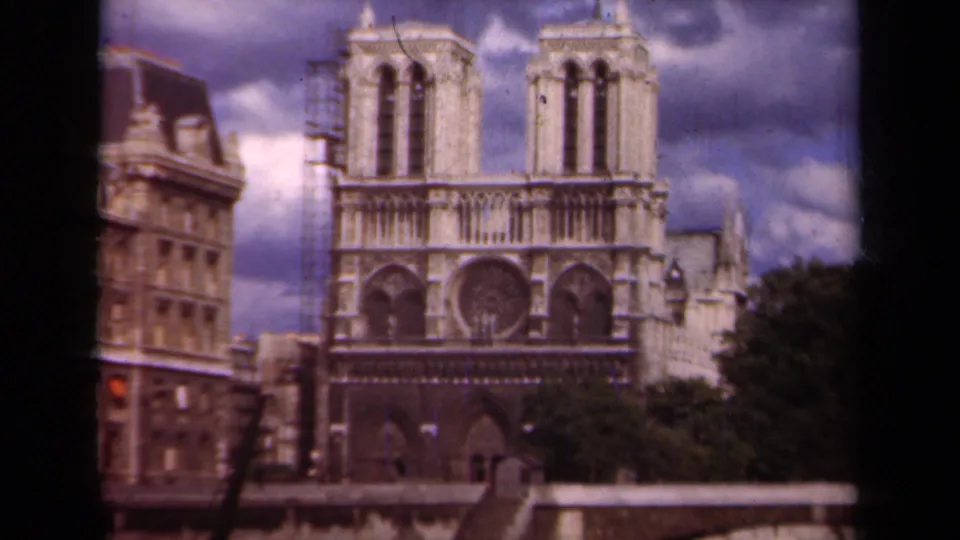 Paris home-movie frame of Notre-Dame Cathedral in 1939, with the facade centered and scaffolding visible along the left tower.