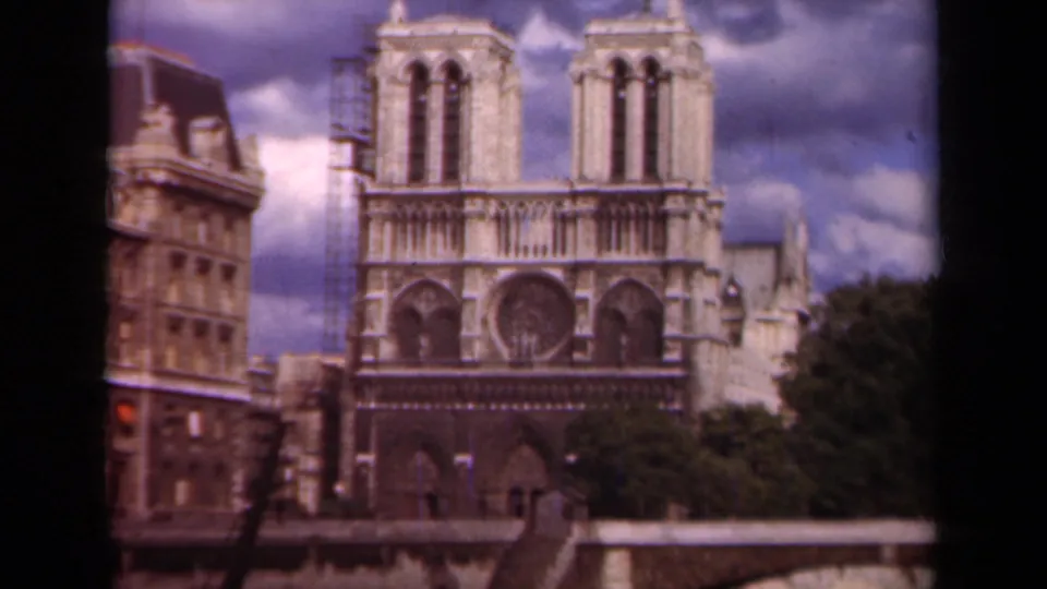 1939 Paris 8mm frame with Notre-Dame Cathedral filling the view, the left tower partly scaffolded and trees at the lower right.