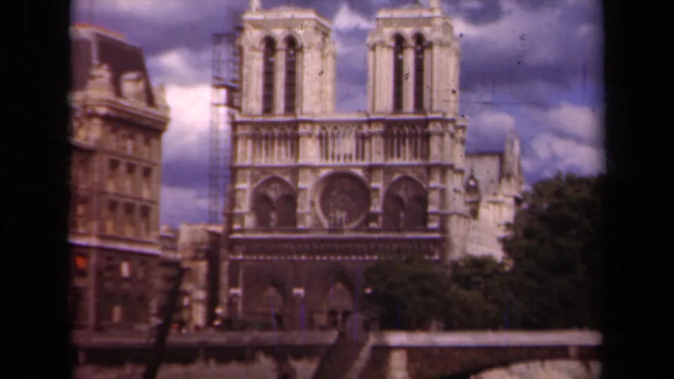 1939 Paris 8mm frame showing Notre Dame Cathedral's west facade, twin towers, rose window, and nearby riverside buildings.