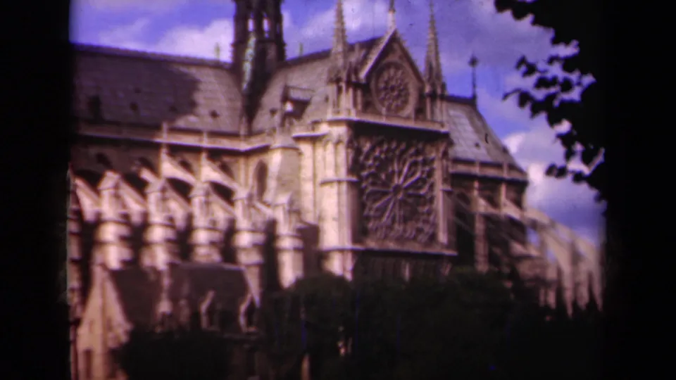 1939 Paris 8mm frame showing Notre Dame Cathedral's side facade, rose window, spires, roofline, and tree silhouettes along the edge.