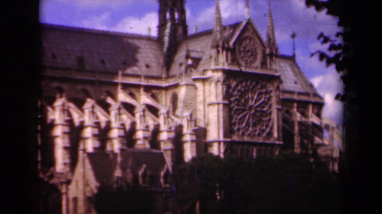 1939 Paris home-movie frame showing Notre-Dame Cathedral's rose window, flying buttresses, roof, and stone facade.
