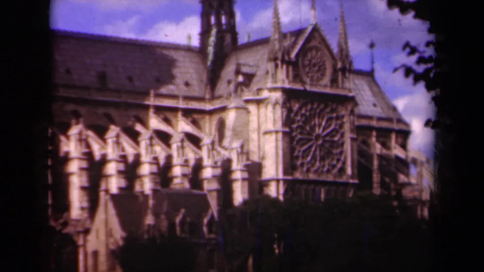 1939 Paris home-movie frame showing Notre-Dame Cathedral's rose window, flying buttresses, roof, and stone facade.