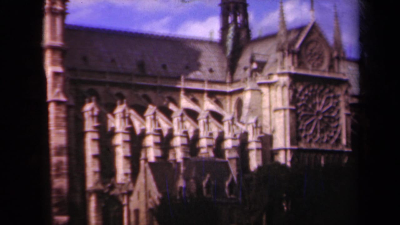 Cathedral exterior with buttresses, rose window, tower edge, and dark foreground shadow.