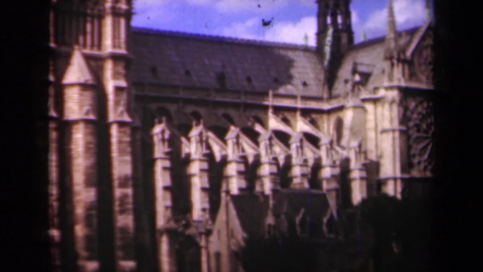 1939 Paris frame showing Notre-Dame's side elevation, stone buttresses, tower masonry, roofline, and partial rose window.