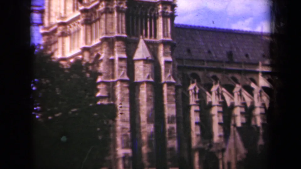 1939 Paris frame of Notre-Dame Cathedral's exterior, showing stone buttresses, tower masonry, trees, sky, and 8mm frame edges.