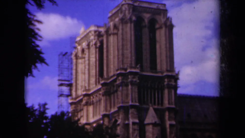 1939 Paris frame of Notre-Dame Cathedral, with Gothic stone details, side scaffolding, clouds, and dark trees enclosing the view.