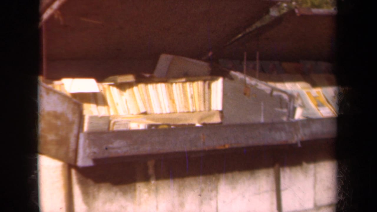 Metal container filled with books and papers beside a wall.