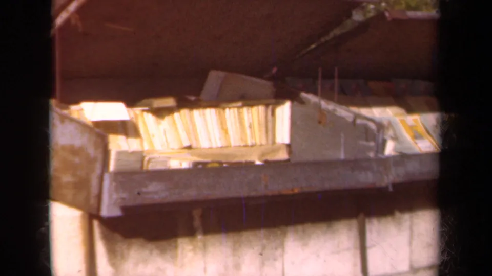 1939 Paris 8mm frame showing a metal trash container holding books or papers beside a masonry wall.