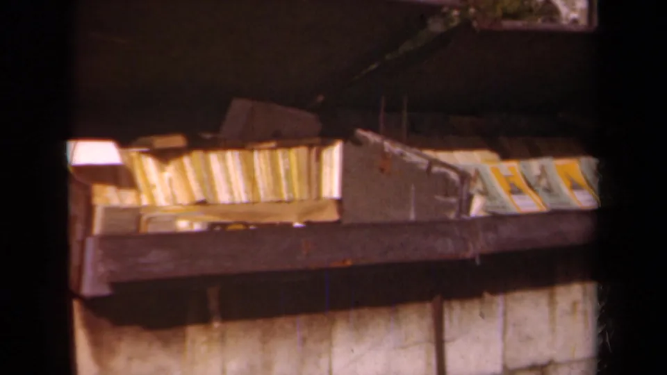 1939 Paris 8mm frame showing books or papers in a metal container below a dark overhang or roofline.