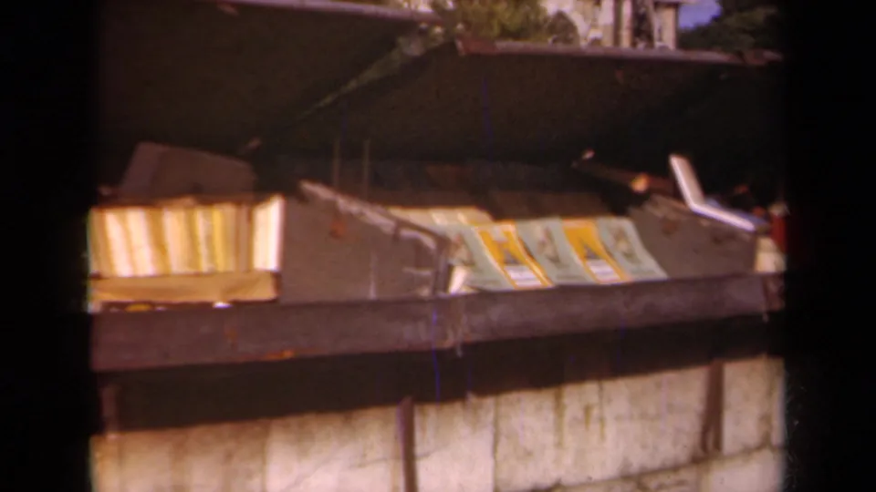 1939 Paris 8mm frame showing folded papers and books in a metal trash container, with masonry and dark edges around the frame.