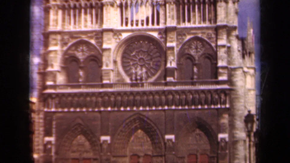 1939 Paris home-movie frame showing Notre-Dame's west facade, rose window, carved arches, and pale Gothic stonework.