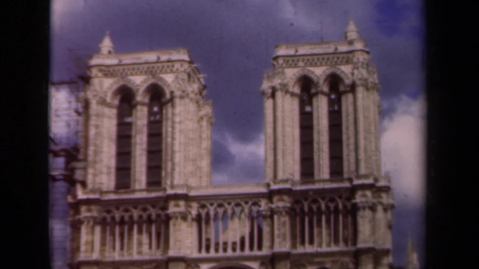 Paris frame of Notre-Dame Cathedral in 1939, with twin towers, upper Gothic facade, blue sky, clouds, and side scaffolding visible.