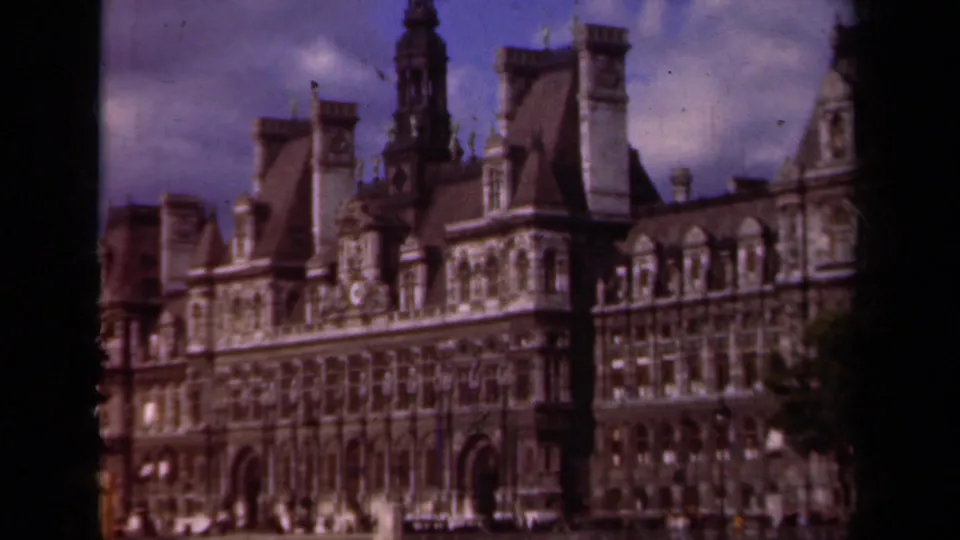 1939 Paris 8mm frame showing the Hôtel de Ville facade with mansard roofs, chimneys, arched openings, and dark film edges.