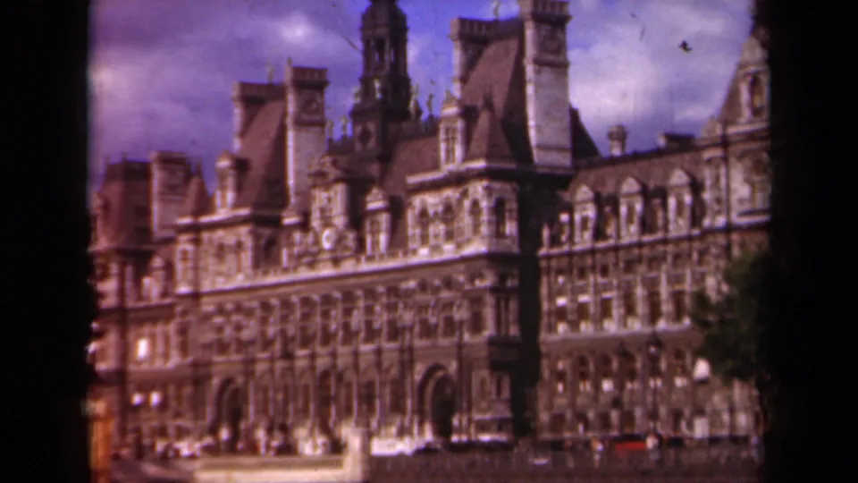1939 Paris 8mm view of the Hôtel de Ville showing ornate stonework, roof towers, arched entries, trees, and small vehicles along the street.