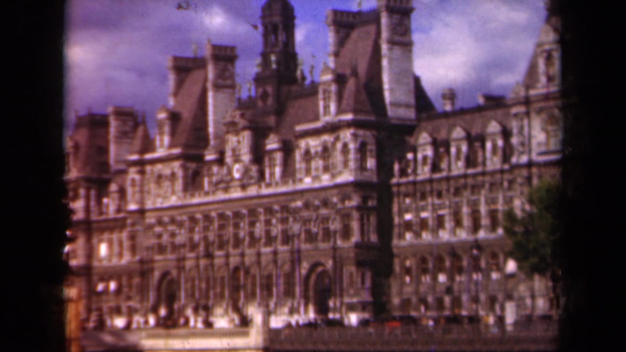 Ornate Hôtel de Ville facade seen from across a street under cloudy sky.