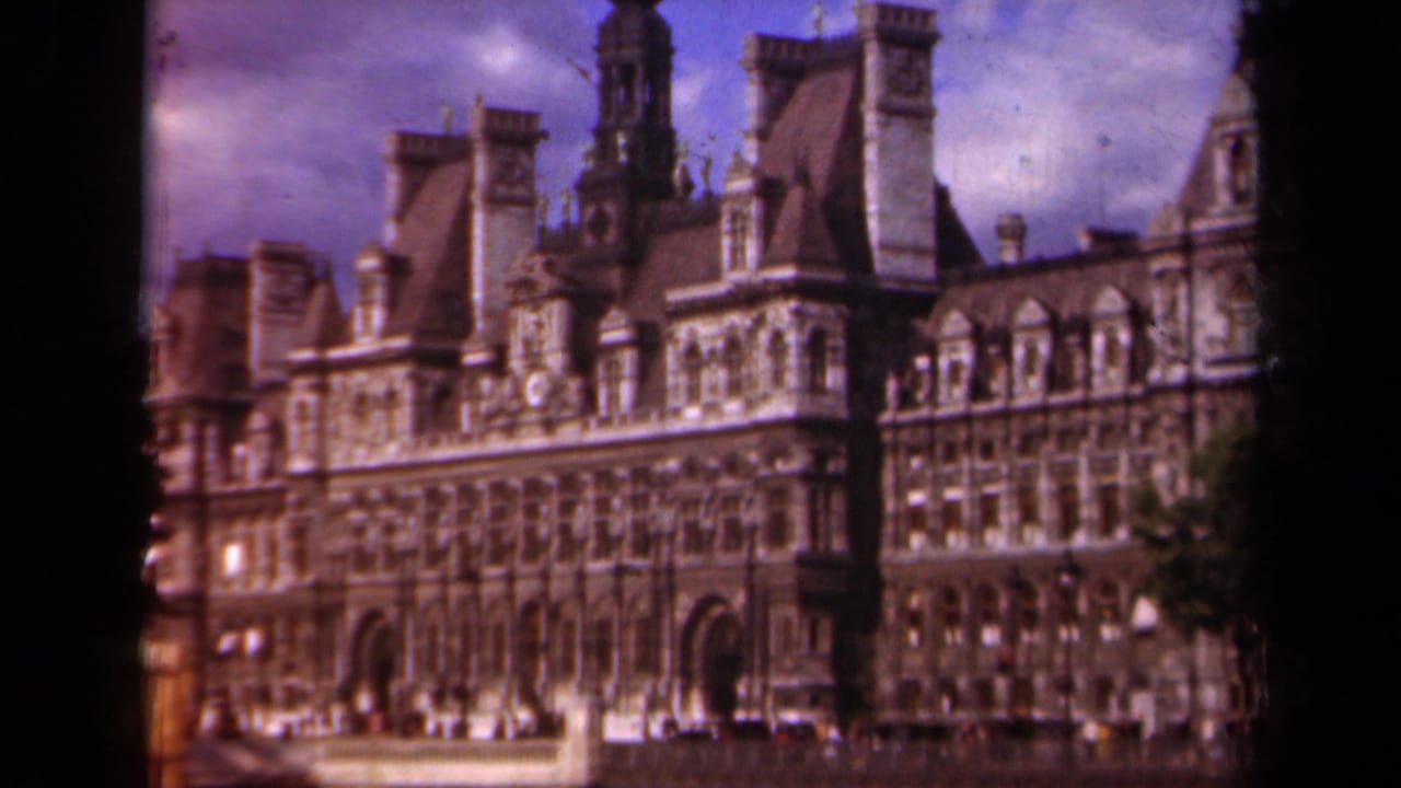 Ornate stone building with towers and arched entries under a purple-tinted sky.