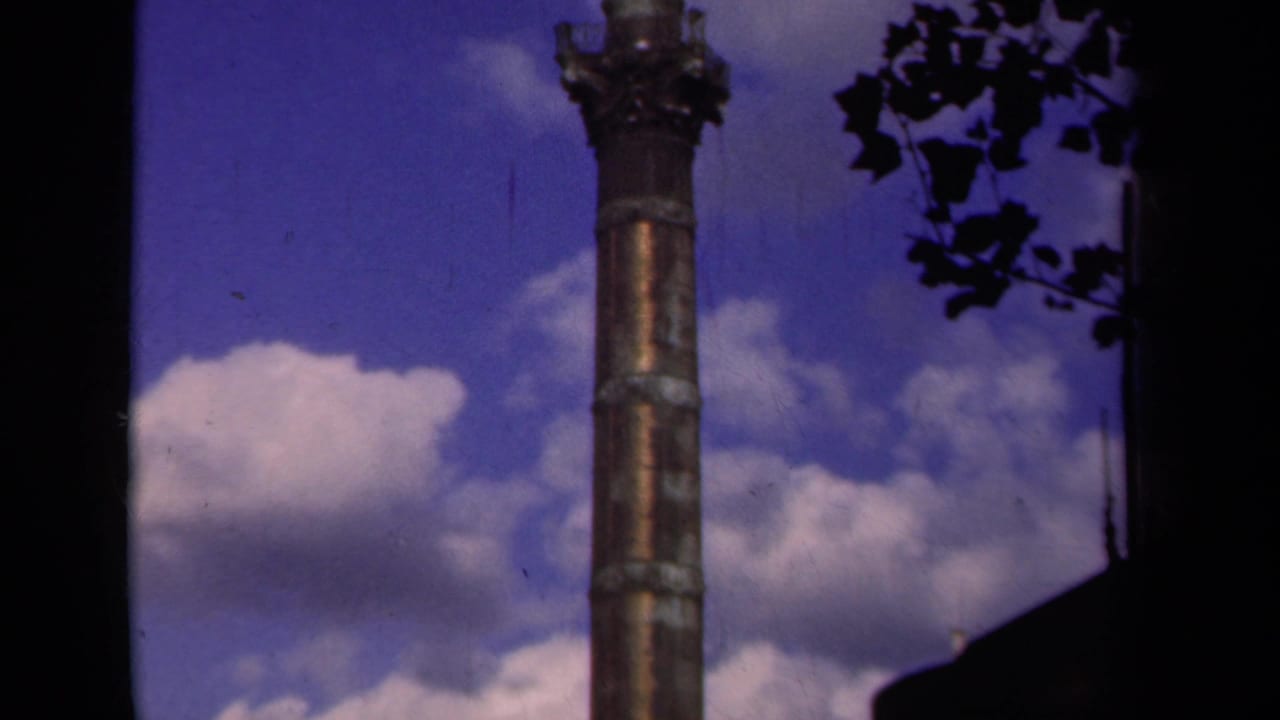 1939 Paris frame showing the upper column and capital area against a clouded sky, bordered by leaves and dark structure.