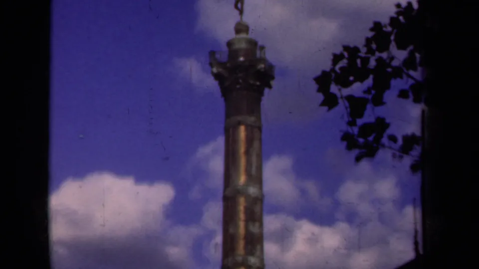 1939 Paris 8mm frame showing a bronze monument with a winged figure above clouds and dark tree silhouettes.